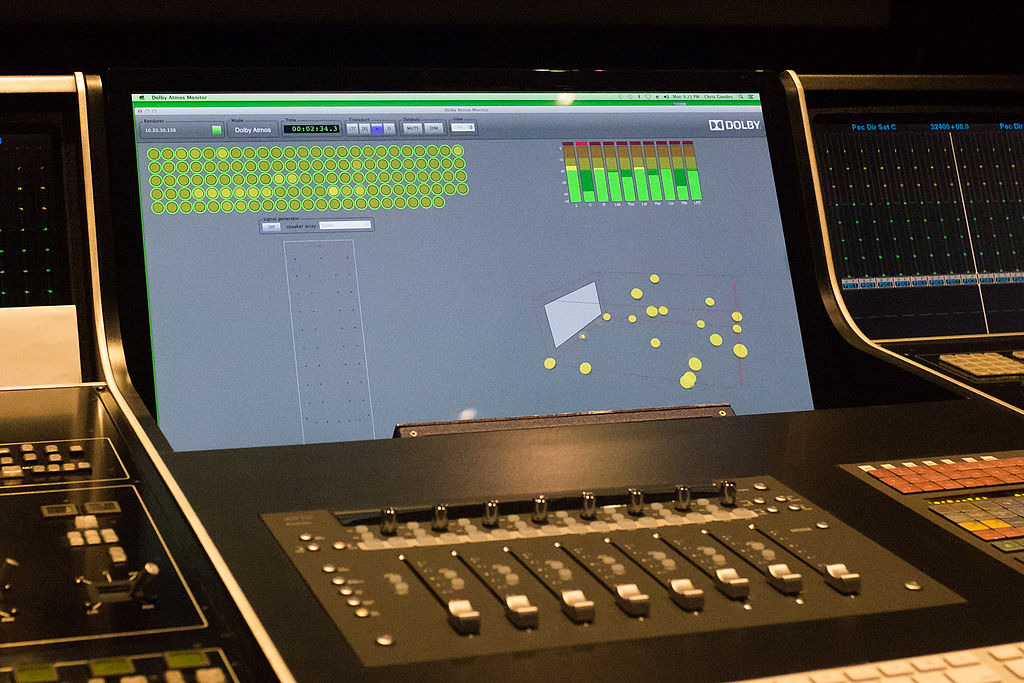 A close-up of a digital mixing console or control surface with a screen displaying Dolby Atmos mixing software. Photo by Nichollas Harrison.