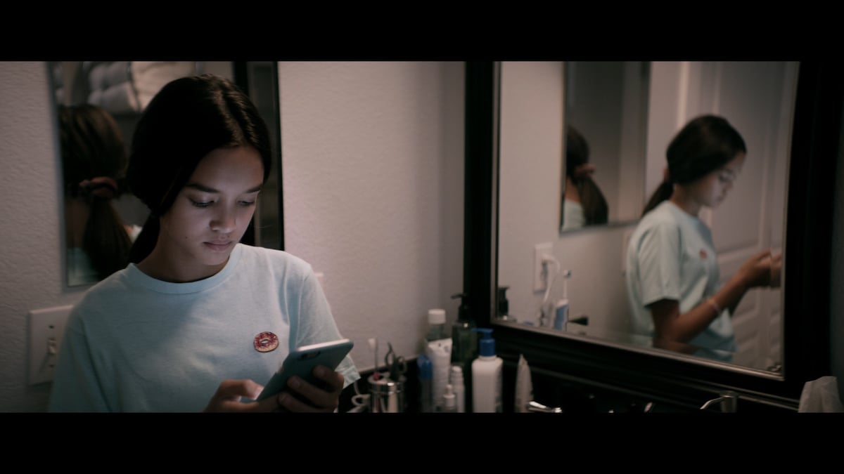 The Social Dilemma still - Isla on phone in bathroom