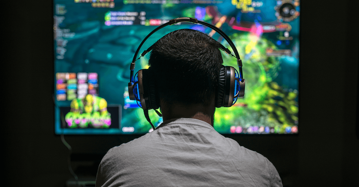 Man in headphones in front of a computer screen.