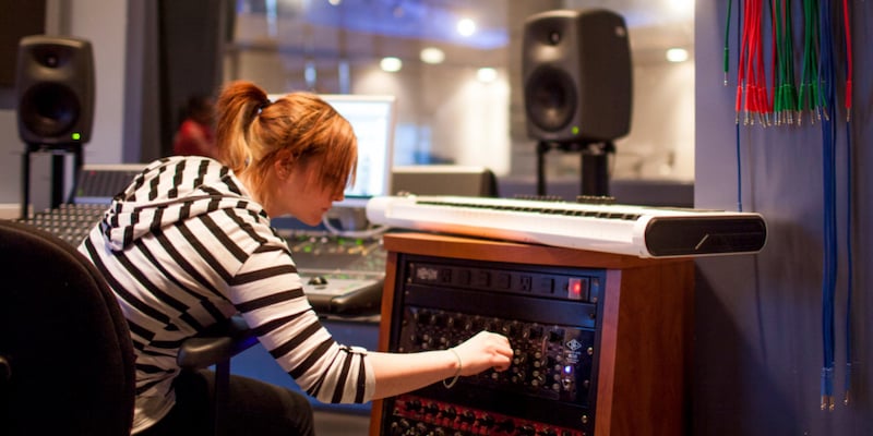 A Student at Savannah College of Art and Design leans over to adjust outboard equipment in one of the school's studio facilities.